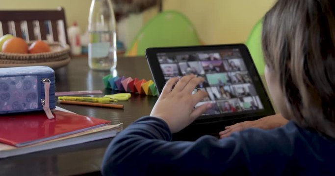 caucasian little girl smart studying at home during coronavirus  quarantine, using tablet,  doing school tasks at home, distance education and home schooling in virtual classroom