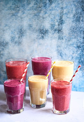 Glasses with colorful smoothies, red, white, yellow, pink