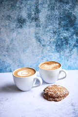 Two cups of cappucino with cookies