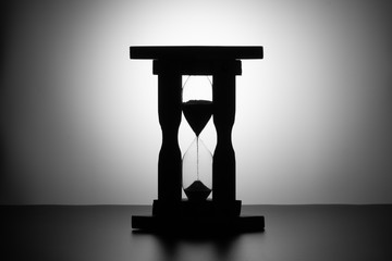 the silhouette of a walking wooden hourglass on a black-and-white gradient background. clearly...