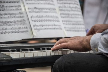 manos tocado piano con partitura de notas musicales al aire libre