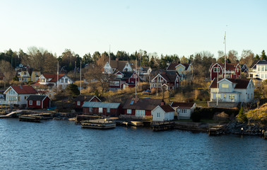 Picturesque summer houses painted in traditional falun red on dwellings island of the Stockholm archipelago in the Baltic Sea in the early morning.