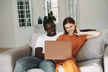 young couple sitting on sofa with laptop