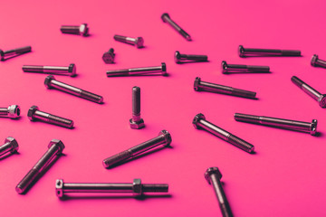 Bolts and nuts closeup on pink background.