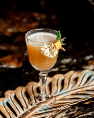 a crystal glass of cocktail garnished with flower and orange zest