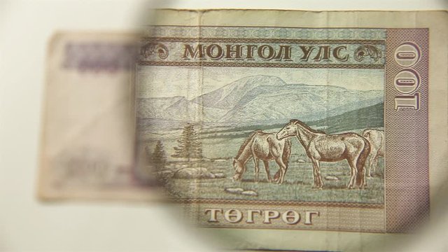 One hundred Mongolian tugriks and a magnifying glass. View a paper bill through a magnifying glass. reverse.
