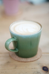 Green cup with coffee on wooden desk