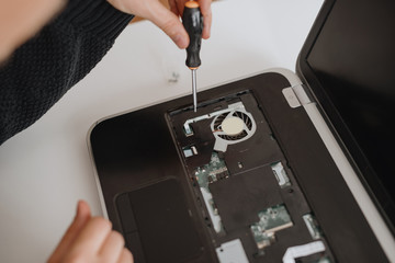 A man disassembles a laptop. Computer service and repair concept. Laptop disassembling in repair shop, close-up. Electronic development, electronic device fixing