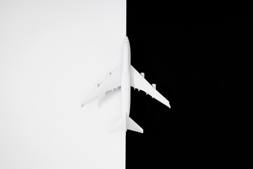 White model plane. Airplane on black and white background. Travel vacation concept. Flat lay, top view, copy space