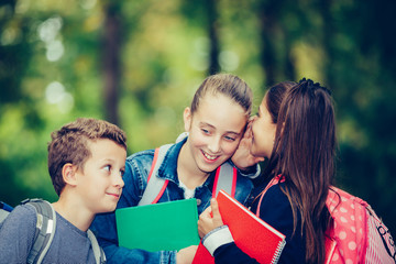 Positive kids whispering a secret each other in the ears.