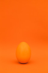 Oranges Osterei vor orangem Hintergrund. Orange easter egg on orange background.