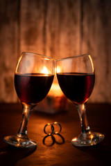 dos copas de vino celebrando con dos anillos en una mesa calida a la luz de la vela