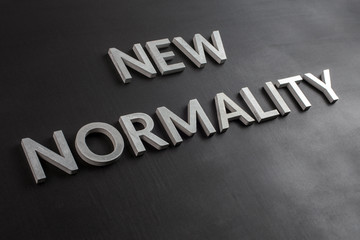 the words new normality laid with silver metal letters on flat black matte surface in slanted...