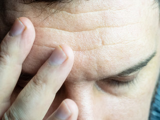 Obraz premium A close-up photo of a man leaning his fingers to his forehead, closing his eyes, showing a headache