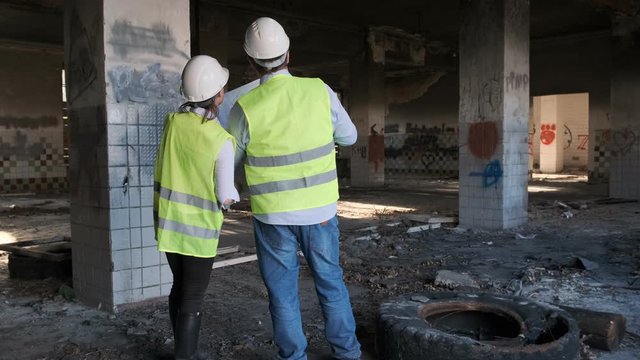 engineer and architect discuss reconstruction plan for dilapidated industrial building