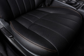 the interior of the car is covered with handmade genuine leather. front car seat. The seat adjustment knob is visible. High-quality stitching with gold threads and skin texture are visible
