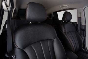 the interior of the car is covered with handmade genuine leather. front car seats. top. head restraints and seat belts are visible. High-quality stitching with gold threads and skin texture visible