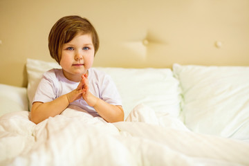 a sweet little girl with blue eyes ,lying in a white bed, under quarantine because of the covid-19 pandemic