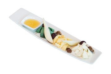 A portion of different types of cheese with slices of pear, nuts and grapes on a white plate. on white background