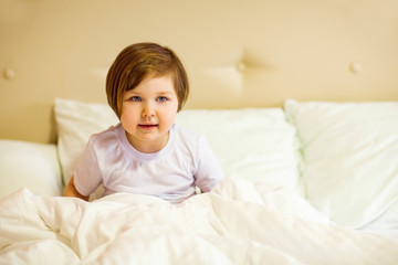 a sweet little girl with blue eyes ,lying in a white bed, under quarantine because of the covid-19 pandemic