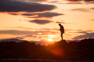 silhouette of a man on a rock at sunset, iceland