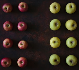 Lines of red and green apples on a brown background.