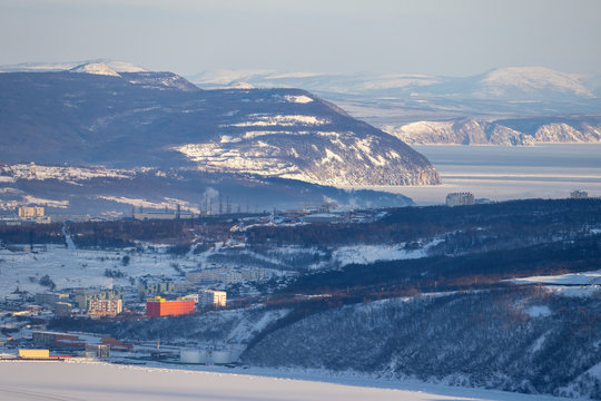 Beautiful winter view of the coast of the Sea of Okhotsk and the surroundings of the city of Magadan. Top view of the sea bays, snow-covered hills and buildings. Magadan, Siberia, Far East Russia. - Powered by Adobe