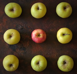 Red and green apples forming a square on a brown background.