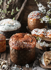 Set of different Easter cake or bread kulich with glaze, chocolate, candy and nuts on rustic wooden background with easter eggs and spring flowers. Happy Easter holiday