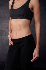 Fototapeta na wymiar Standing woman in black sportwear, belly closeup