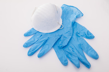 Pair of latex medical gloves and surgical ear-loop mask on blue background. Protection concept
