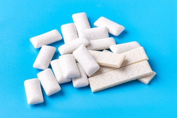 Chewing gum top view macro photography on a blue background. A lot of gum is scattered on the table.