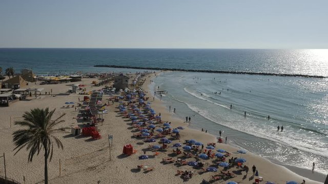  tel aviv Active sunny day with people on the beach People sunbathing on crowded beach, waves rolling onto seashore, sunny summer.
