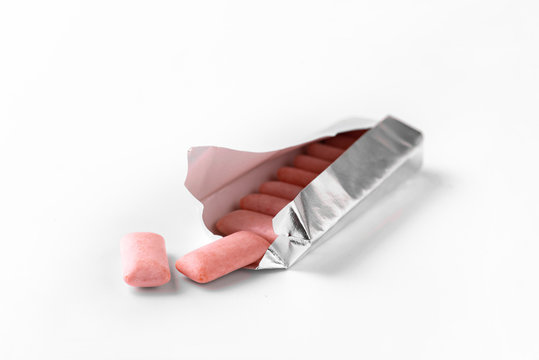 Pink chewing gum drops out of the package. White background.