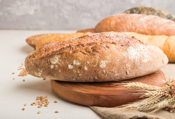 Different kinds of fresh baked bread on a white wooden background. side view, selective focus.