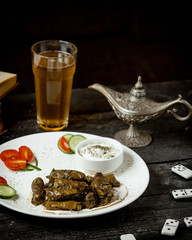 a plate of grape leaves dolma served with yogurt cucumber and tomato