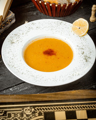 a plate of lentil soup garnished with dried mint and lemon