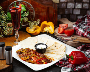 a platter of beef fajitas served with flatbread and sauce