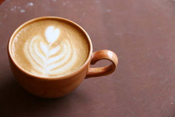 cappuccino with latte art on brown background