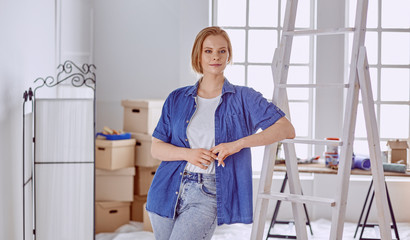 Beautiful young woman on a white wooden stepladder. Ready to repair the room. Women housework concept