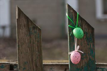 Colored Easter eggs with ribbons hang on an old wooden fence close-up. Easter concept