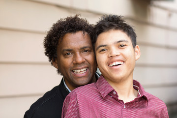 African American father hugging his son and smiling.