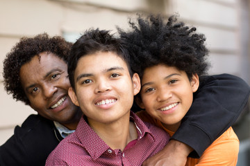 African American father hugging his two sons. - Powered by Adobe
