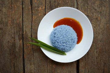 Sticky rice, coconut jam and pandan leaves on plate on wooden table