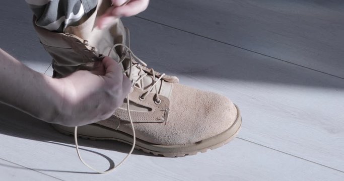 Soldier's hands lace up his shoes. Timelapse