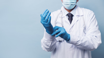 A male doctor in a medical mask puts on rubber gloves. remedies for infection and coronovirus