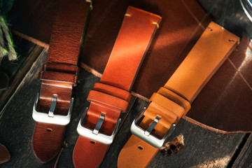 Brown leather handmade watch straps with steel buckles on dark rustic wooden table near to. the...