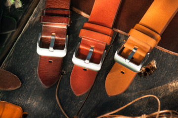 Handmade watch straps on wooden rustic surface. Different leather colour tones. Closeup.