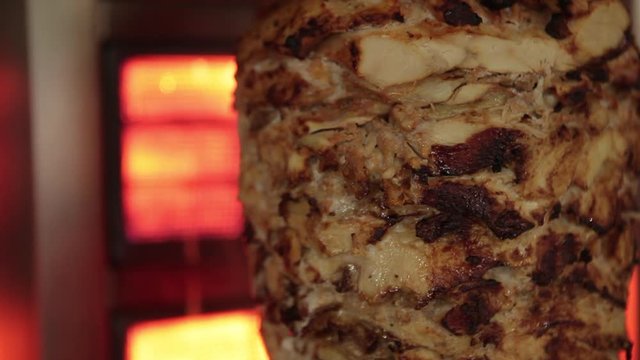A cook cuts meat to make shawarma, gyros, doner kebab. Cooking meat on a skewer