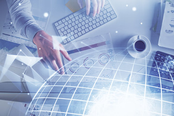 Multi exposure of man's hands typing over computer keyboard and world map hologram drawing. Top view. Technology concept.